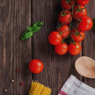 Bright red tomatoes & a package of pasta on a wooden table