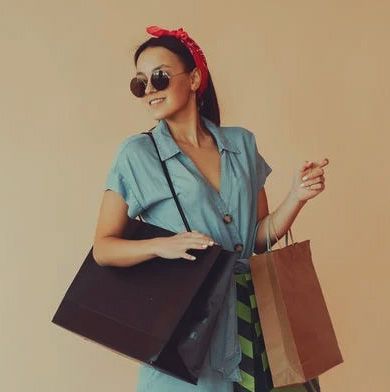 A well-dressed woman wearing sunglasses and carrying a large purse and a shopping bag